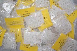 White M8 nylon flat washers inside clear grip seal bags, complete with a yellow information label.